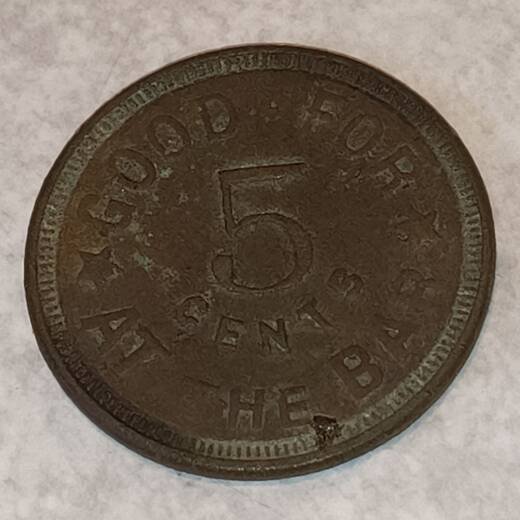 Worn brass token reading Good for 5 cents at the bar around a large numeral 5, with stars between the words
