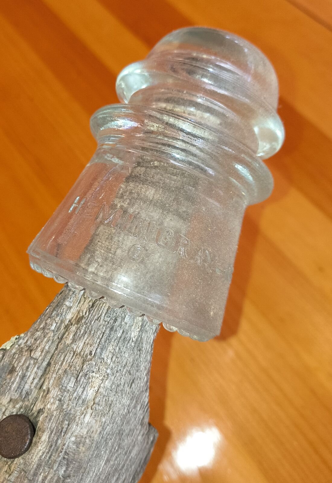 Close view of a clear glass insulator showing the embossed word Hemingray and beaded drip points along the base